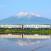 Juna Gono Line -rautatien varrella, taustalla vuori ja edessä vettä